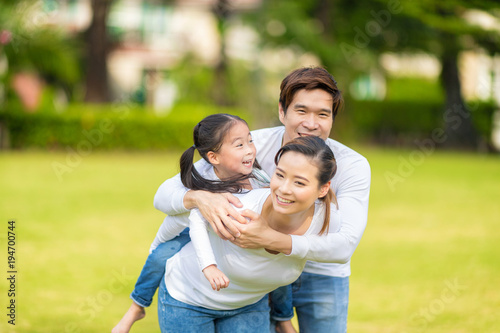 Cute Asian girl on neck parents big happy laughing and run around together.Happy family piggybacking adorable little daughter is smiling.