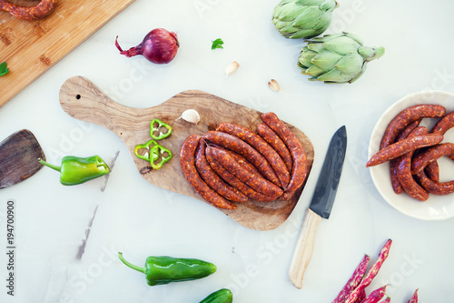 Raw lamb sausages with spices on a white background, flat, top view. Traditional merguez with vegetables