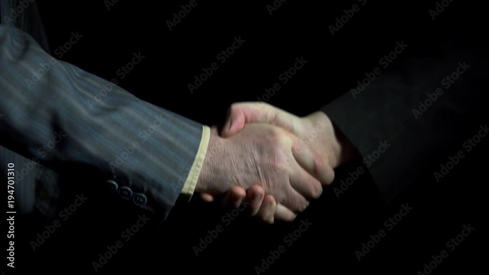 Handshake of businessmen wearing suits on a black background, close-up 4k Handshake of businessmen wearing suits on a black background, close-up 4k