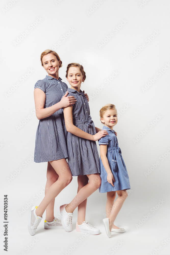 mother and daughters in similar dresses standing in row on white mother and daughters in similar dresses standing in row on white