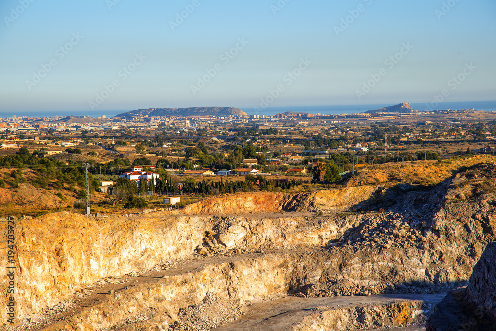 Exacavacion minera a cielo abierto con panoramita a la huerta de alicante y con el fondo el mar mediterraneo