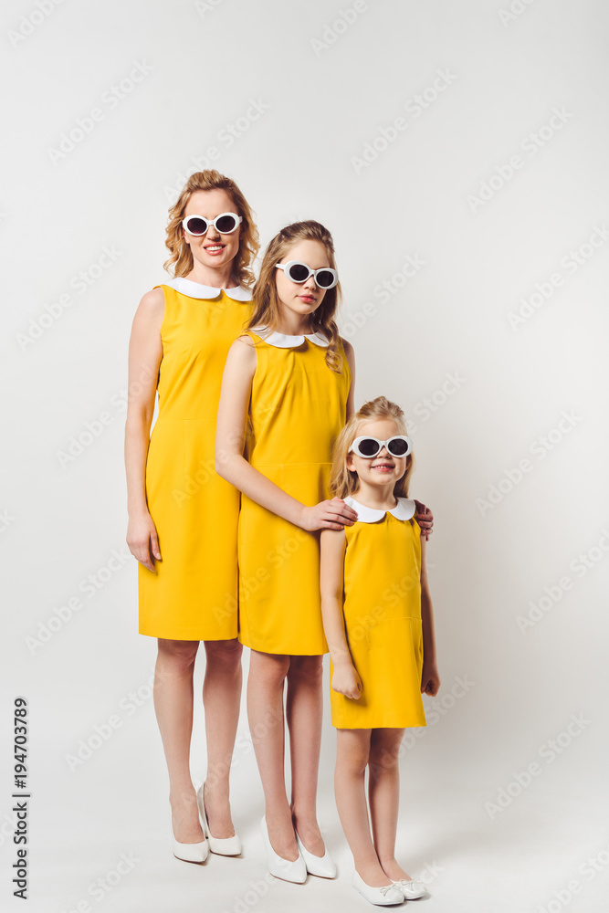 mother and daughters in similar retro style yellow dresses in row on white mother and daughters in similar retro style yellow dresses in row on white