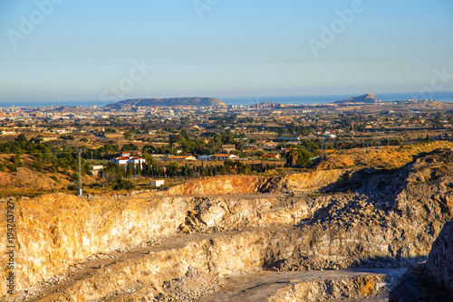 Exacavacion minera a cielo abierto con panoramita a la huerta de alicante y con el fondo el mar mediterraneo