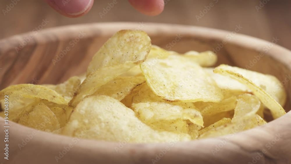 Slow motion closeup man hand take potato chip from wood bowl