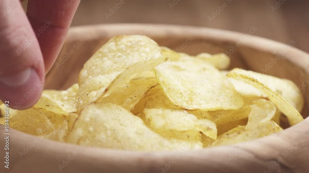 Slow motion closeup man hand take potato chip from wood bowl Slow motion closeup man hand take potato chip from wood bowl