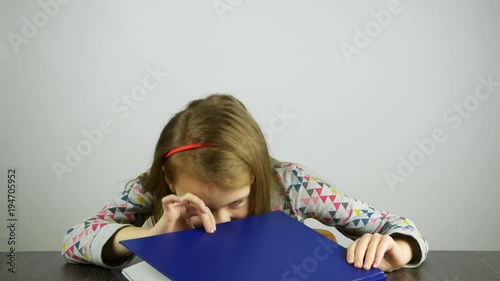 The girl peeks in the book and looks surprised. The concept of children's 