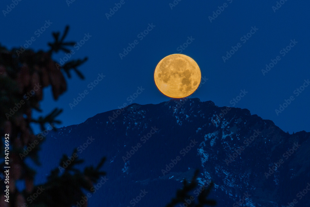 Fototapeta premium Vollmond versinkt hinter den Bergen