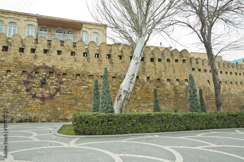 .Gate of the old fortress, entrance to Baku old town. Baku, Azerbaijan. Walls of the Old City in Baku . Icheri Sheher Old, or Inner Town . Clock on the town wall. People making pictures photo