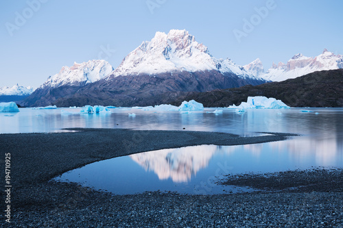 Floating icebergs in a lake and high mountains covered in snow in the background photo