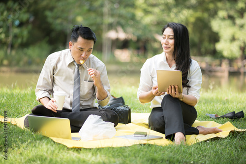 Selective focus business couple relaxing with tablets in park after work done © ic36006