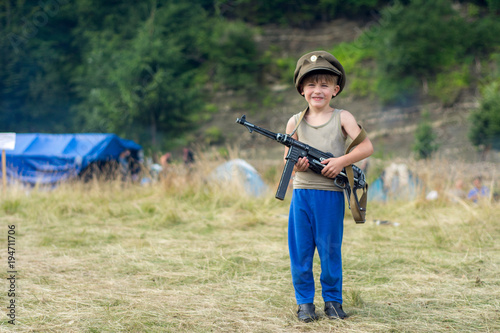 A little boy in his cap holds a trophy weapon MP-40 from the Second World War