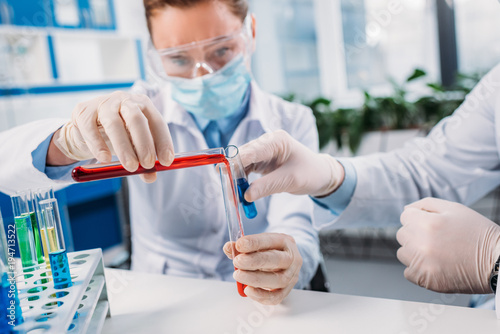 selective focus of scientists mixing reagents in tube in lab