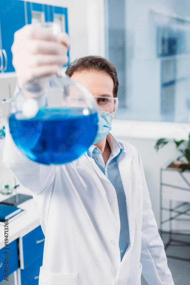 selective focus of scientist with flask in hand in lab