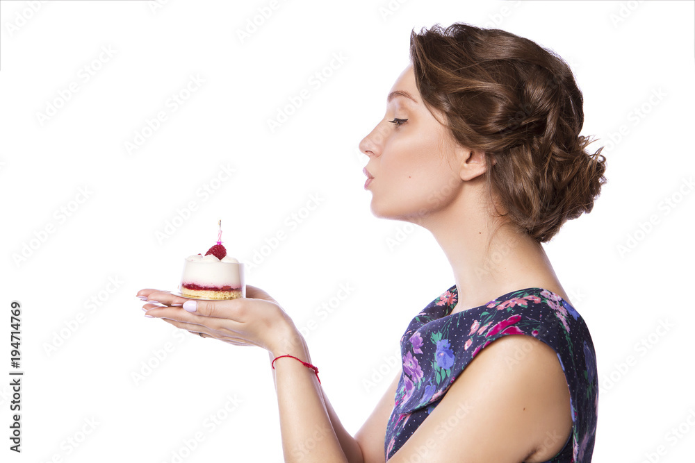 Brunette pretty beautiful caucasian woman in blue festive dress blowing candle on a birthday party cupcake. Isolated white background Brunette pretty beautiful caucasian woman in blue festive dress blowing candle on a birthday party cupcake. Isolated white background