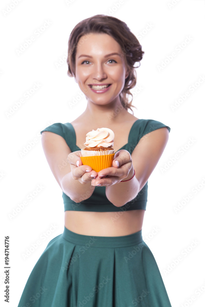 Brunette pretty beautiful caucasian woman in green festive dress showing proposing holding sweet cupcake dessert in her palms. Isolated white background Brunette pretty beautiful caucasian woman in green festive dress showing proposing holding sweet cupcake dessert in her palms. Isolated white background