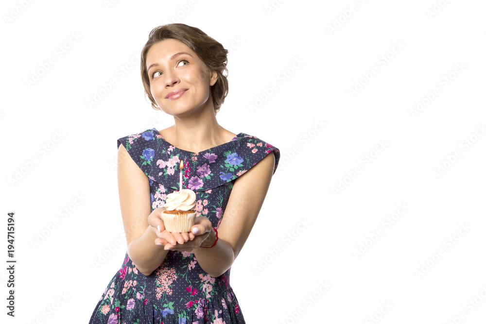 Brunette pretty beautiful caucasian woman in blue festive dress blowing candle on a birthday party cupcake. Isolated white background Brunette pretty beautiful caucasian woman in blue festive dress blowing candle on a birthday party cupcake. Isolated white background