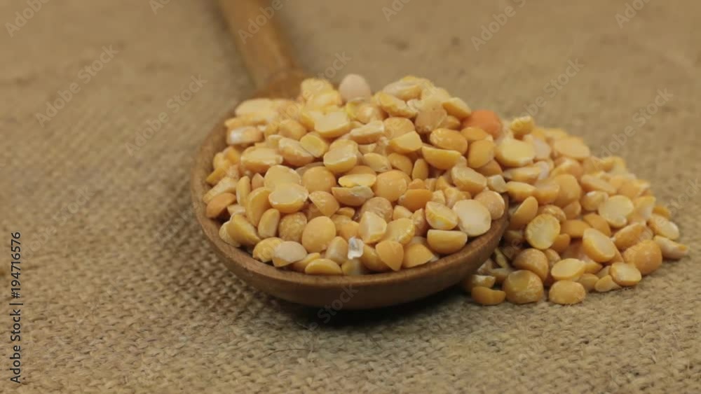 Rotating a spoon, overflowing with dry peas grains, lying on burlap. Rotating a spoon, overflowing with dry peas grains, lying on burlap.