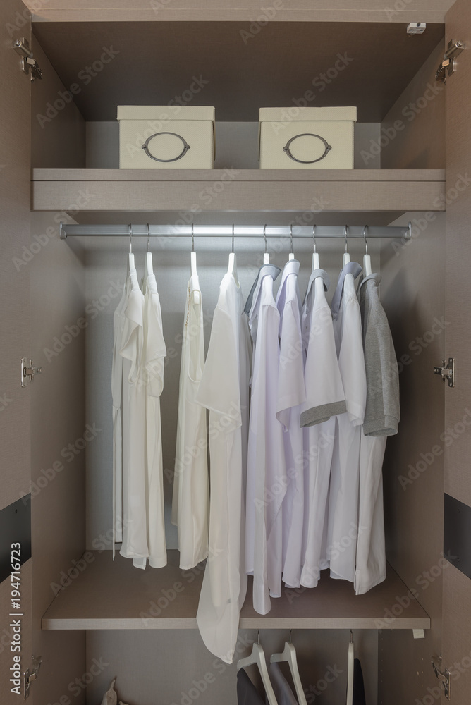clothes hanging on rail in wooden wardrobe clothes hanging on rail in wooden wardrobe