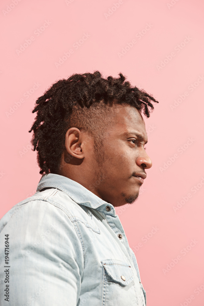 The suspicious business Afro-American man standing and suspiciously looking against pink background. Profile view. The suspicious business Afro-American man standing and suspiciously looking against pink background. Profile view.