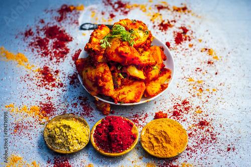 Indian appetizer dish i.e.Teekha Laal Batata or Spicy potato with  all its ingredients and spices on a sliver wooden surface.This dish is popularly eaten with crunchy fired sticks Bhongla. photo