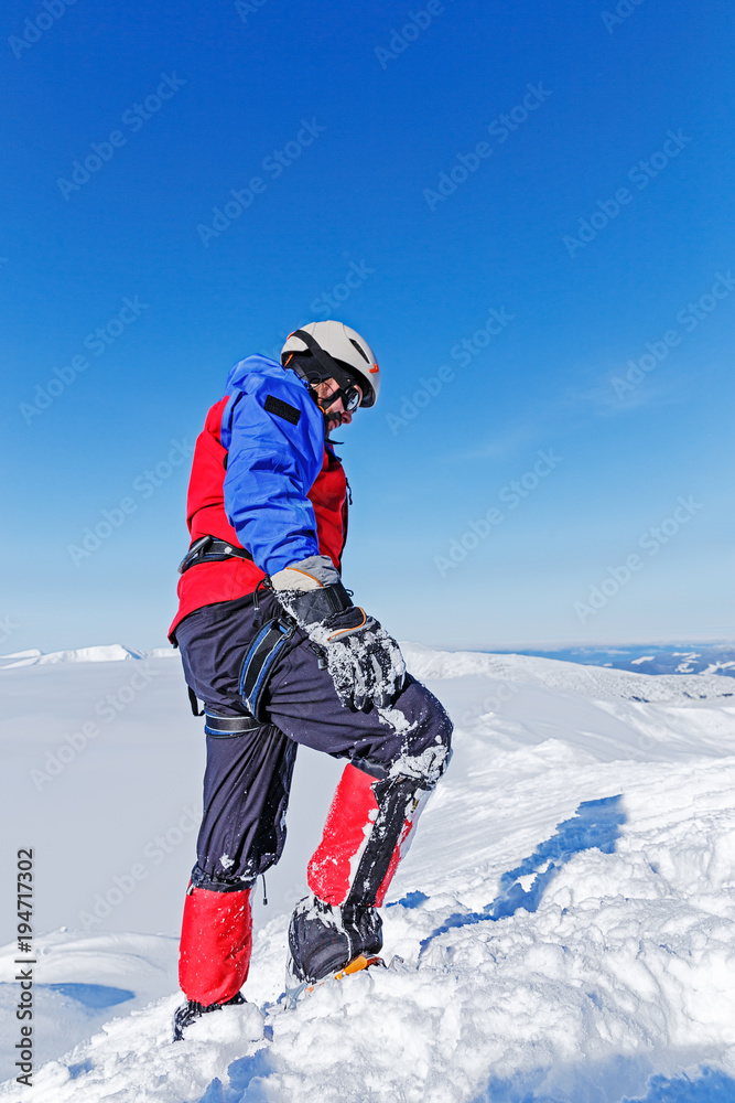 Equipped climber ascent on the top of peak in snowy alpine mountains. Life guard professional man on the work in high mountains.