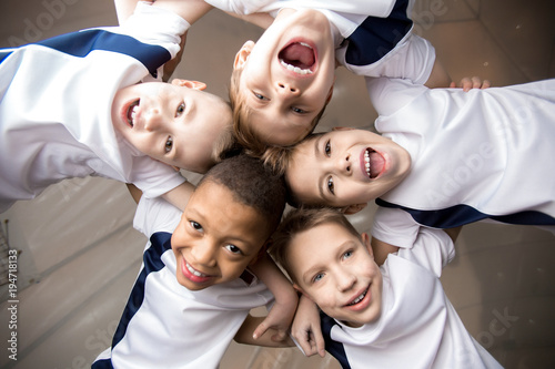 Photos Below view of five young football players in uniform making head by head circle