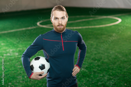 Young confident football trainer in sportswear looking at camera while standing on pitch © pressmaster