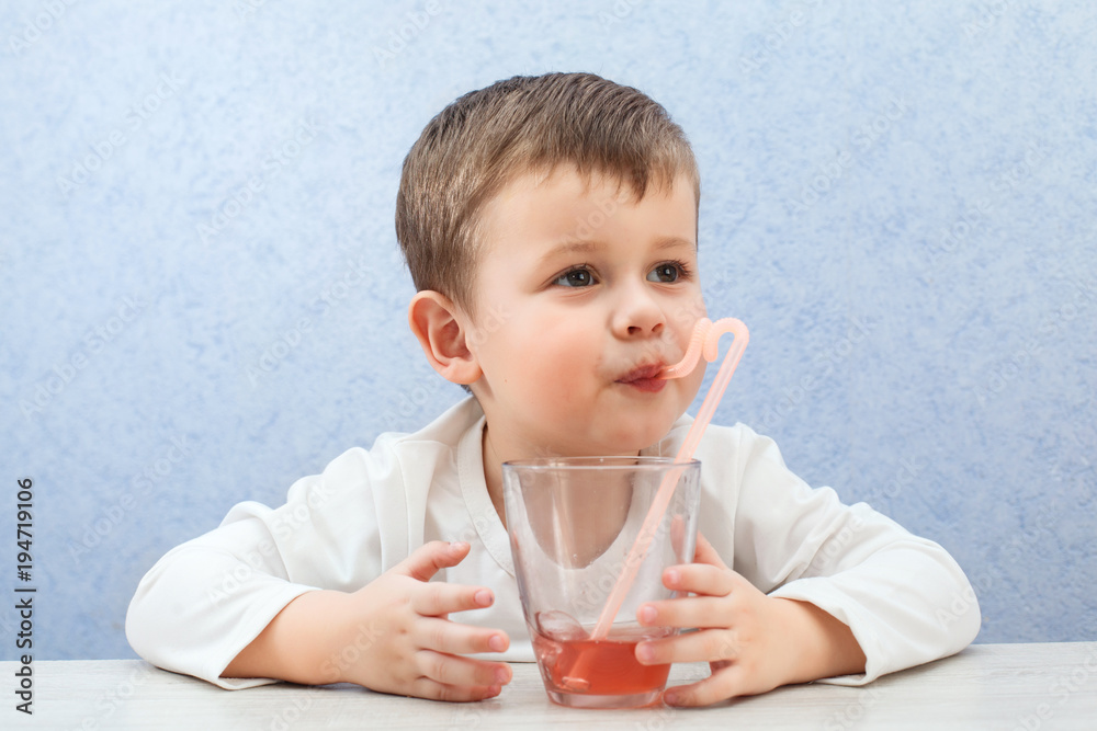 Cute little boy drinking juice on light blue background. Lovely kid drink grape juice. Cute little boy drinking juice on light blue background. Lovely kid drink grape juice.