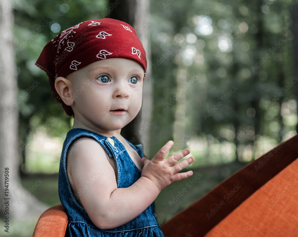 A portrait of a nice little baby girl with blue eyes, wearing a red bandana.  Stock Photo | Adobe Stock