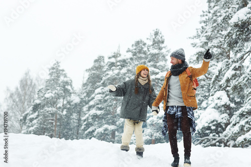 Young travelers enjoying their trip in winter forest on snowy day