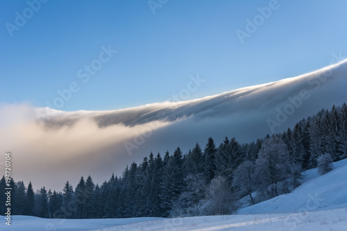 Winterlandschaft mit schnee und Nebel am Berg und blauem Himmel