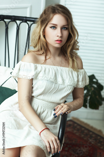 Beautiful model wearing white dress is posing in an interior studio 