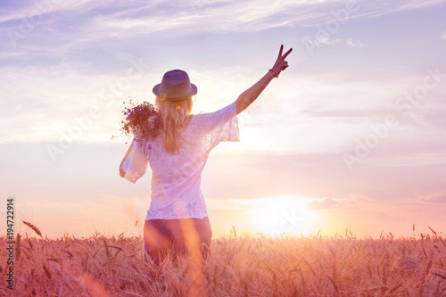 Fotografie Teenage girl feels freedom and relaxing outdoors, enjoying nature with the sunrise field of wheat