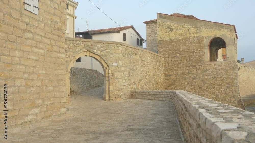 Stone wall, arched gate and old buildings Stone wall, arched gate and old buildings