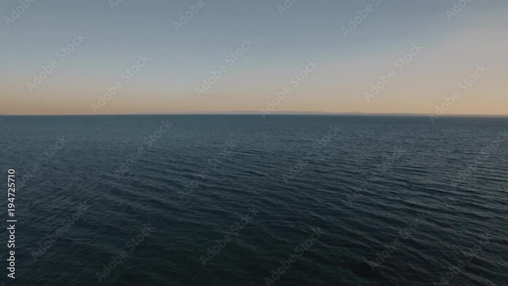 Flying over deep rippling sea at sunset. Vast blue water space and skyline Flying over deep rippling sea at sunset. Vast blue water space and skyline