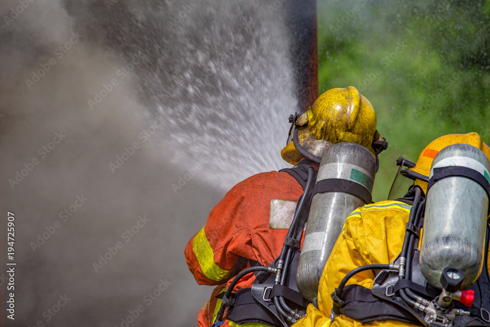 Fototapeta premium two firefighters water spray high pressure nozzle to fire and smoke with copy space