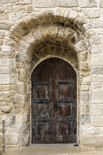 Large, beautiful wooden door in the wall of the old building. Close up. © alexsaz