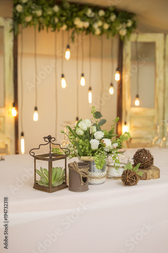 Simple but luxury rich table setting for a wedding celebration in nice cozy restaurant. Wineglasses, plates and bouquet of summer seasonal flowers on a table. Sunlight from a window. Copy space