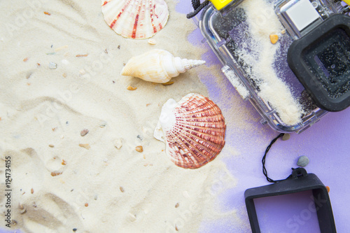 Vacation concept. White tropical sand and seashells, camera underwater case, top view, flat lay photo