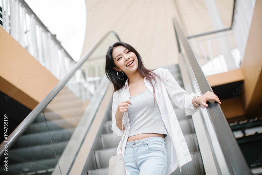 Woman taking escalator in shopping mall