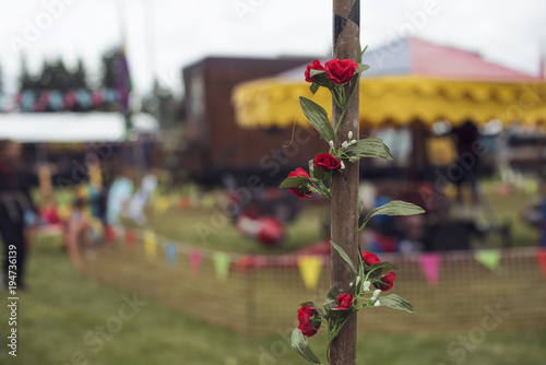 Detalle de rosas rojas enrolladas en poste de madera de una feria/celebración callejera. photo
