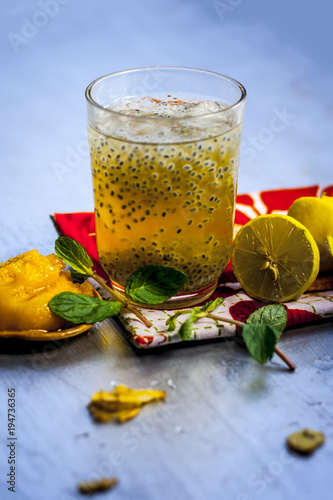 Close up of INDIAN popular summer drink JAGGERY SHRABAT/gud ka shrabat with all its ingredients i.e. lemon,ginger juice, soaked sweet basil, some mint leaves & Jaggery/gud. photo