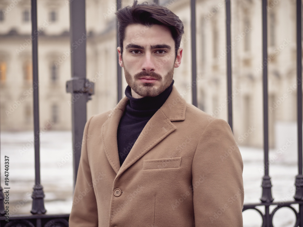 Handsome young man standing outside in winter, in snowy Turin, in Italy, in urban setting Handsome young man standing outside in winter, in snowy Turin, in Italy, in urban setting