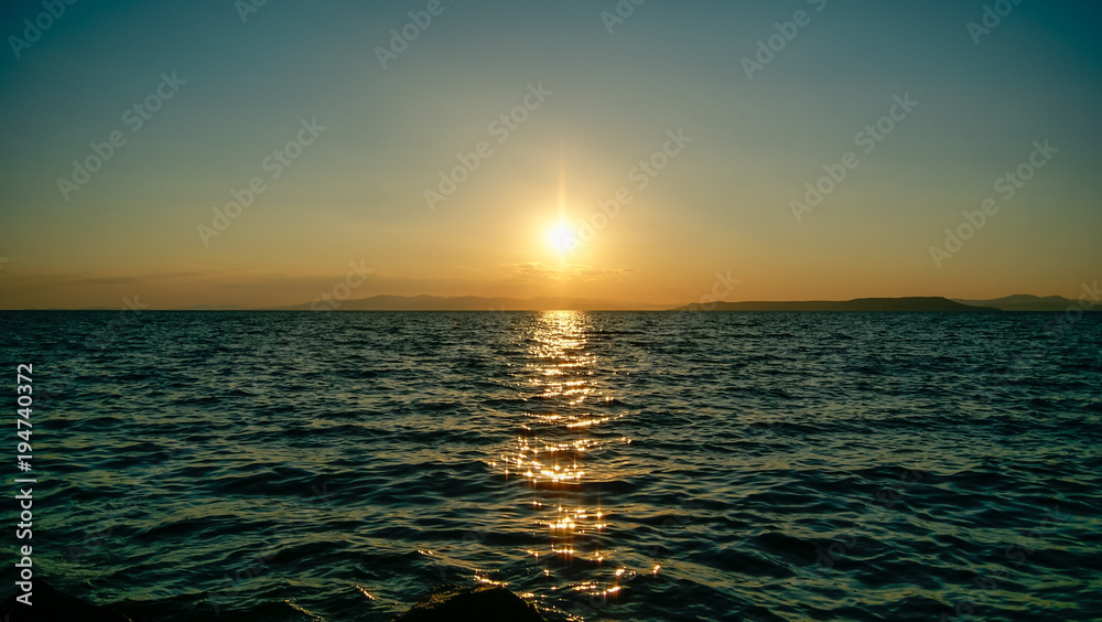 Obraz premium Sunset at sea, against islands