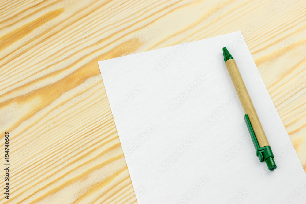 Sheet of white paper mockup with pen on wooden background Sheet of white paper mockup with pen on wooden background