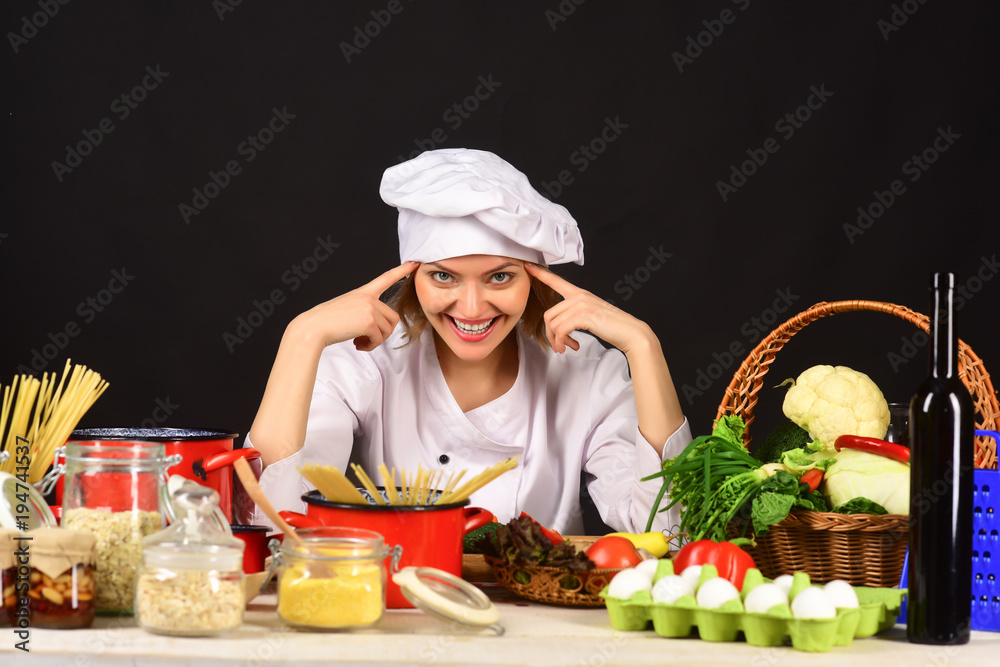 Beauty woman chef. Female chef with bunch of vegetable. Cheerful attractive woman chef is sitting at table with bunch of vegetable and thinking what to cook. Beauty woman chef. Female chef with bunch of vegetable. Cheerful attractive woman chef is sitting at table with bunch of vegetable and thinking what to cook.