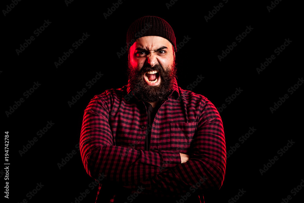 Bearded man screaming in anger on black background in studio photo Bearded man screaming in anger on black background in studio photo