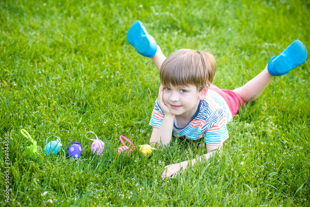 Little boy hunting for easter egg in spring garden on Easter day. Cute little child with traditional bunny celebrating feast Little boy hunting for easter egg in spring garden on Easter day. Cute little child with traditional bunny celebrating feast