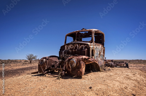 Australia – Outback desert with an old vintage abandoned car near the track under blue sky