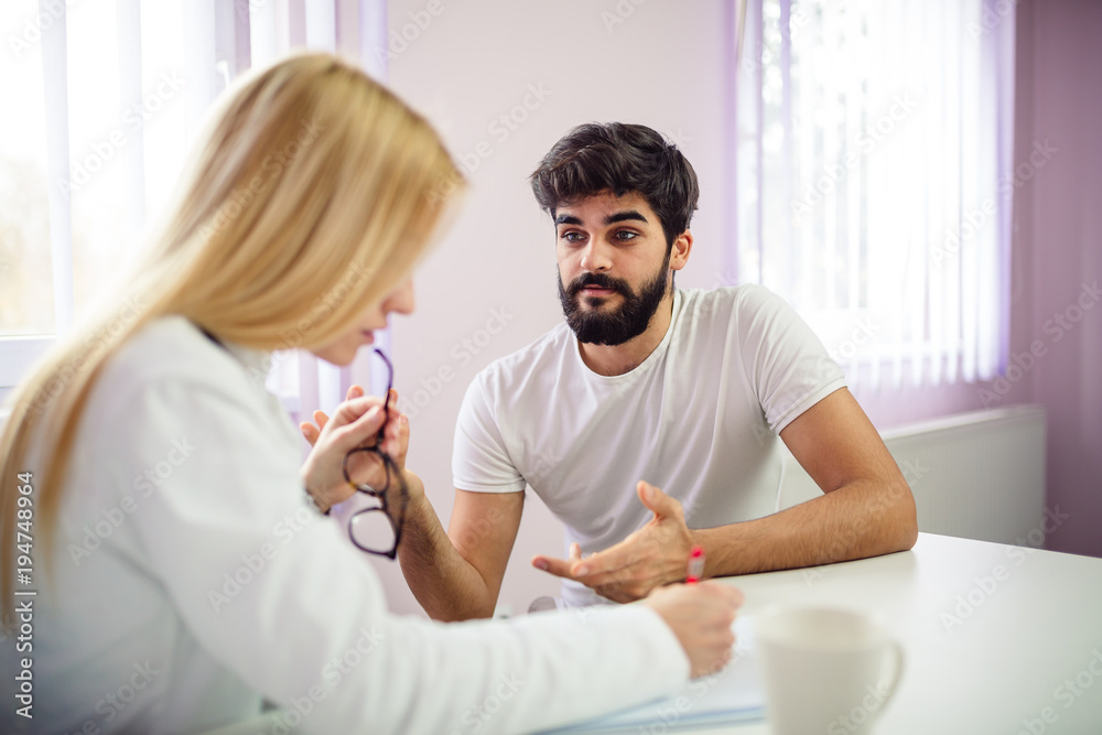 Obraz premium Handsome male patient talking with his doctor.